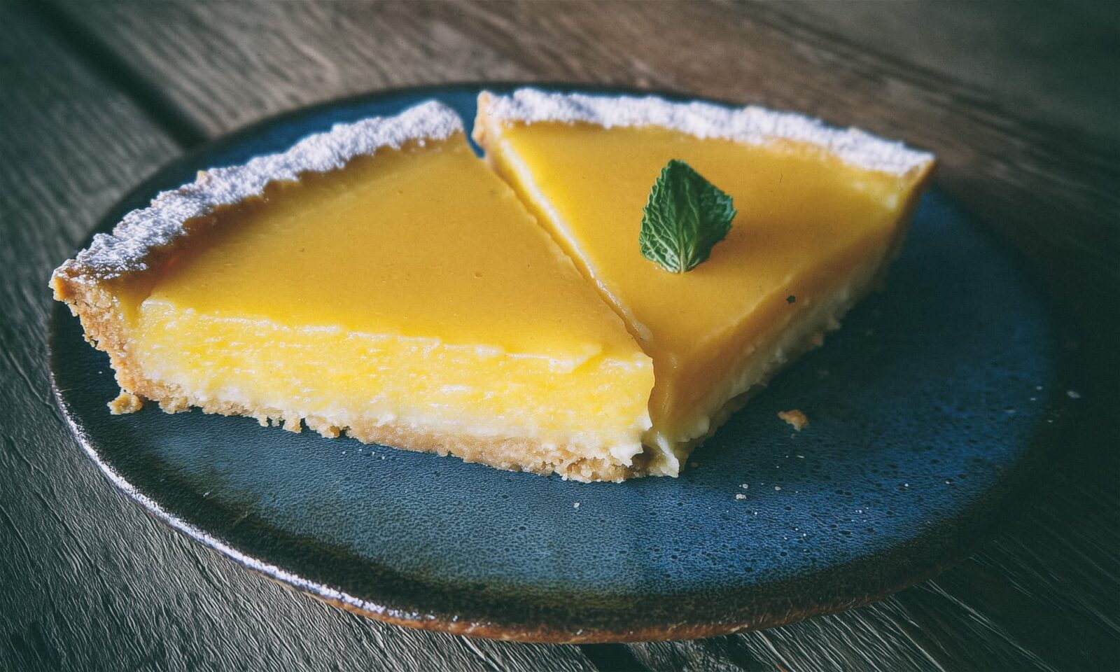 Lagani tart od limuna na plavom keramičkom tanjuru.