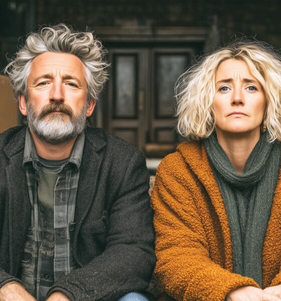 Razvedeni bračni par sjedi usred dnevne sobe pune kutija spakirane i podijeljene imovine.