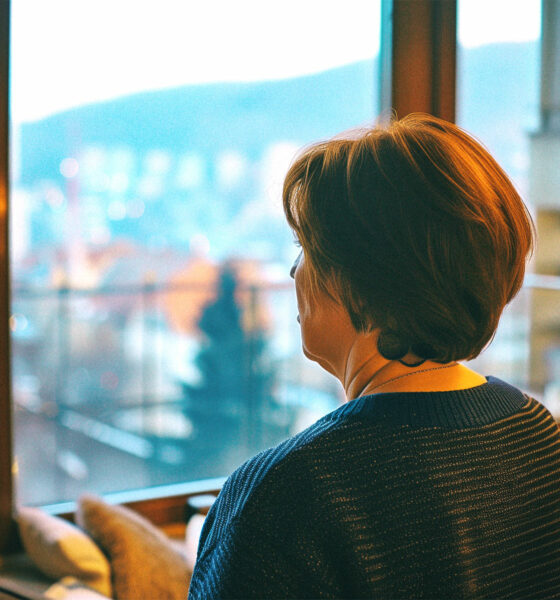 Žena stoji kraj prozora i gleda u zagrebačku panoramu.