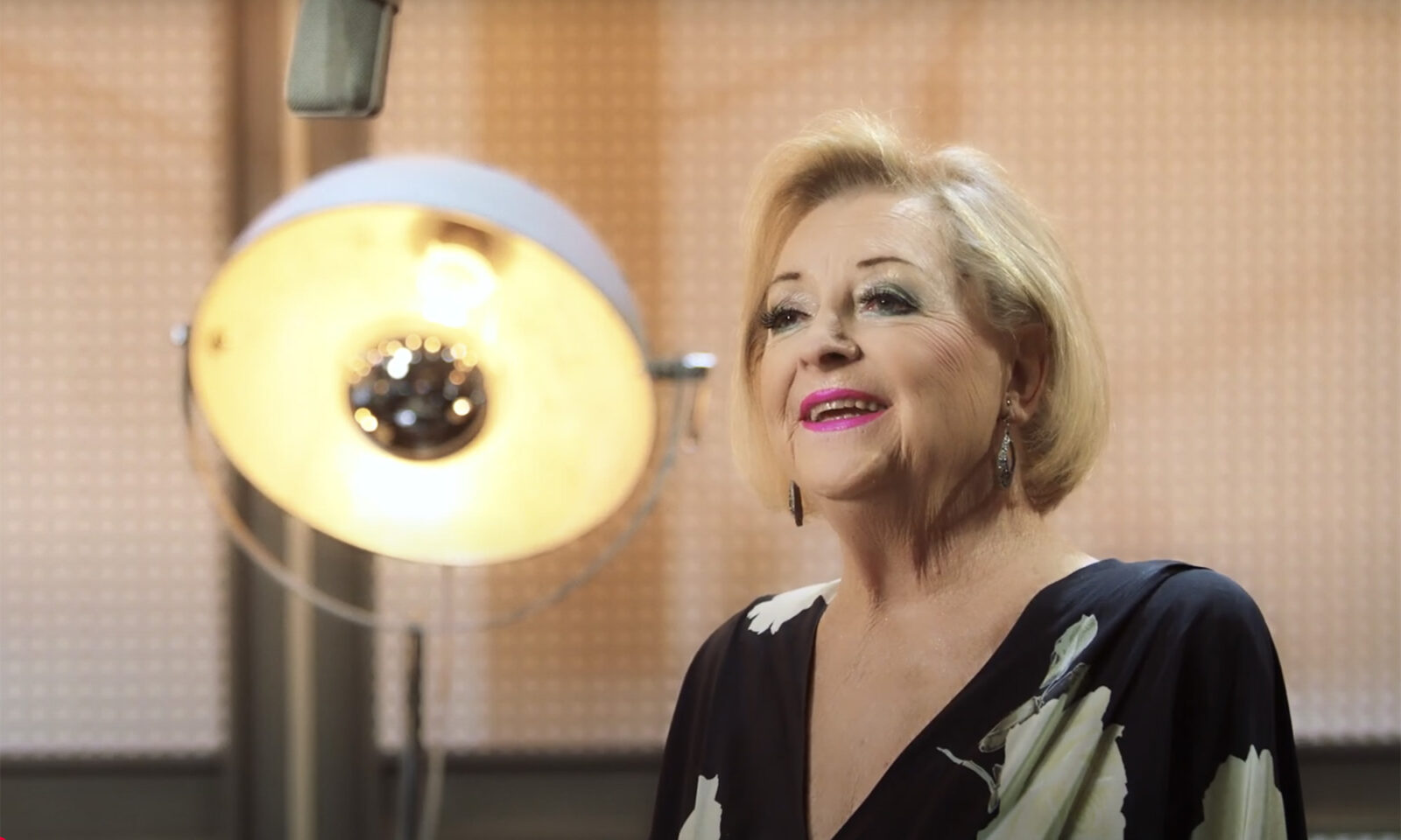 Glazbena diva Gabi Novak u studijskom okruženju – zrači elegancijom, osmijehom i profinjenom prisutnošću pred mikrofonom.