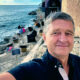 Enver Čišić, umirovljenik, snima selfie uz obalu mora na kamenoj terasi s jastucima i pogledom na Jadran.