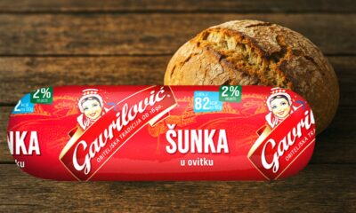 Gavrilović šunka u ovitku s oznakom 2 posto masti, ispred svježe pečenog kruha na drvenoj podlozi.