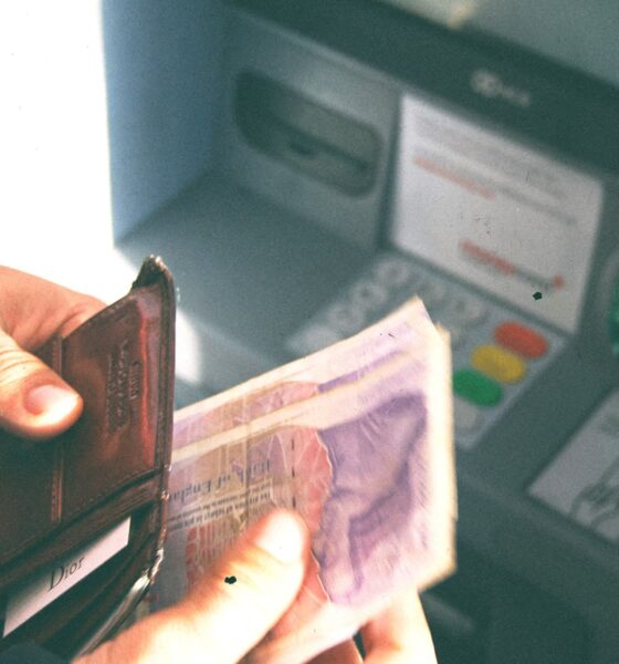 Osoba u ruci drži novčanik s novčanicama, podiže novac s bankomata.