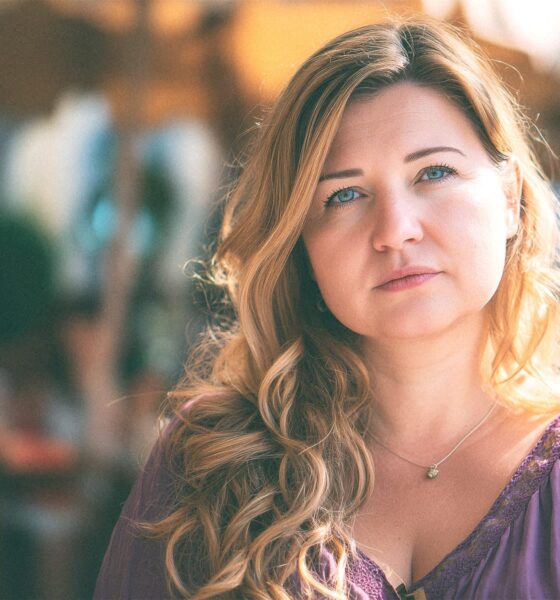 Mlada žena duge kose i plavih očiju sjedi u kafiću.