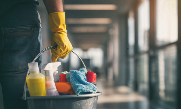 Muškarac drži kantu sa sredstvima za čišćenje u ruci.