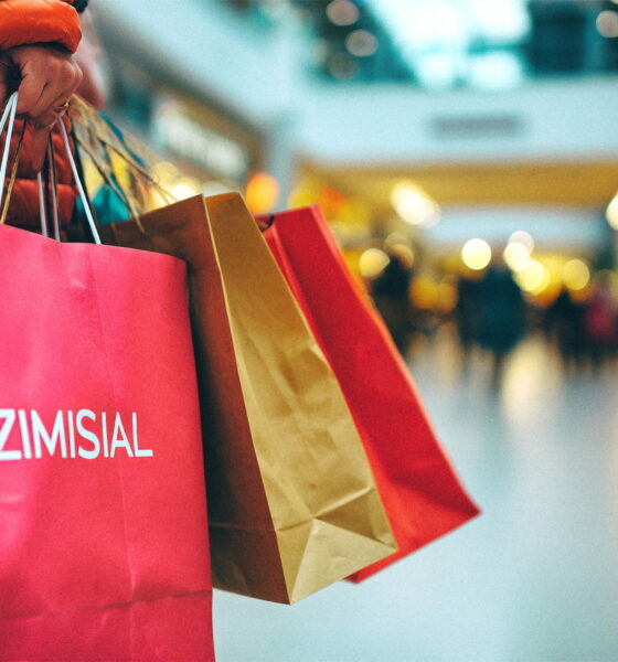 Žena u trgovačkom centru nosi pune ruke vrećica s kupljenom robom.