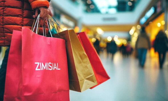 Žena u trgovačkom centru nosi pune ruke vrećica s kupljenom robom.