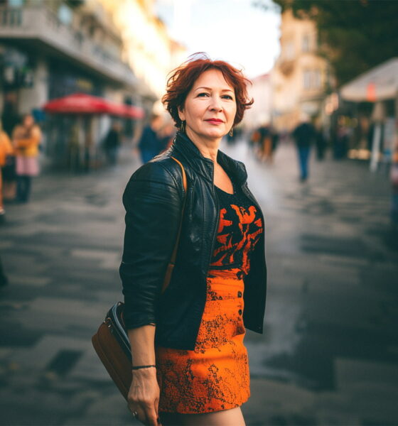 žena u kratkoj suknji i kožnoj jakni, pozira na ulici.