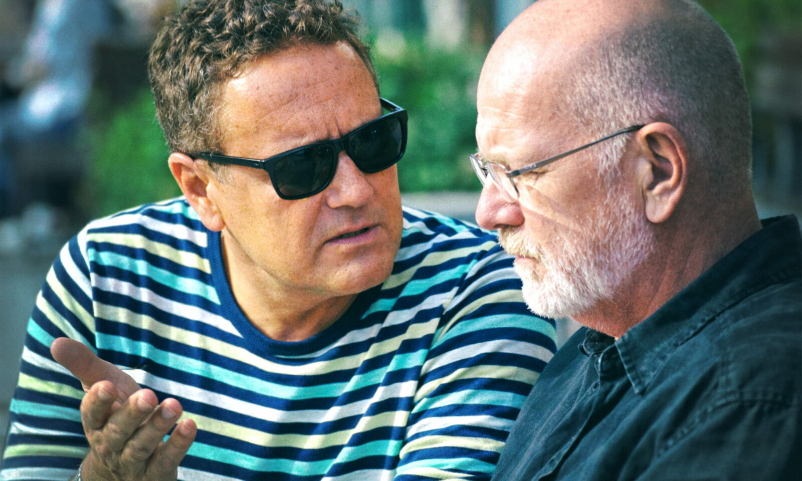 Dvojica prijatelja sjede na klupi i ozbiljno razgovaraju.