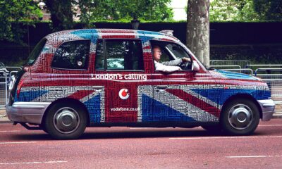 Stariji muškarac vozi reklamni taxi u Londonu.