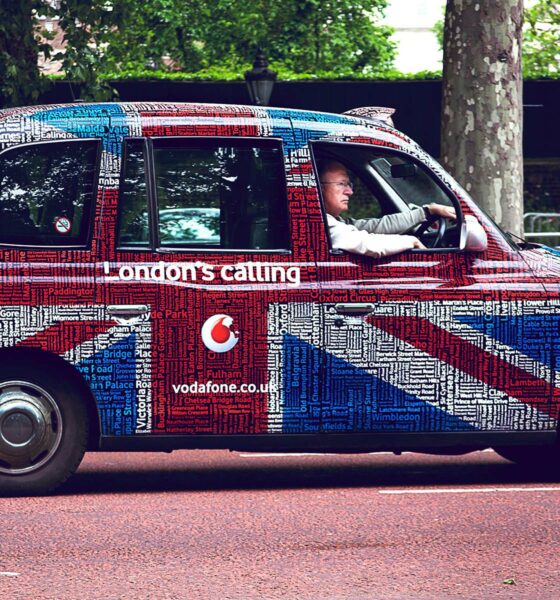 Stariji muškarac vozi reklamni taxi u Londonu.