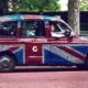 Stariji muškarac vozi reklamni taxi u Londonu.