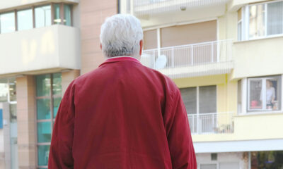 Muškarac stoji na ulici i gleda u stambenu zgradu.