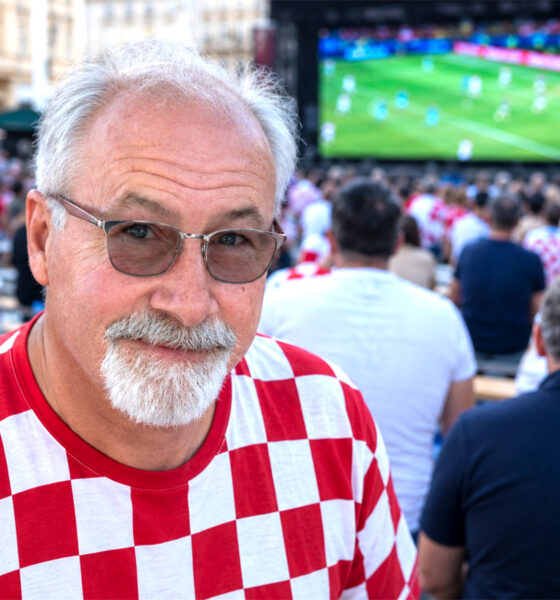 Muškarac u dresu hrvatske nogometne reprezentacije u navijačkoj atmosferi.