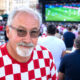 Muškarac u dresu hrvatske nogometne reprezentacije u navijačkoj atmosferi.