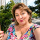 Starija žena na zagrebačkoj ulici snima selfie mobitelom, uz koketan izraz lica i šarenu ljetnu odjeću.