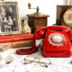 Stari obiteljski predmeti, fotografija, knjige, porculan i crveni telefon na stolu u hrvatskom domu.