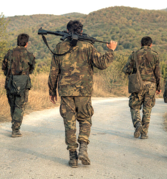 Petorica hrvatskih branitelja u maskirnim uniformama hodaju seoskom cestom, dok jedan preko ramena nosi pušku.