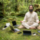 Bradati guru meditira u šumi okružen laptopima, mobitelima, routerom, punjačima i kabelima.