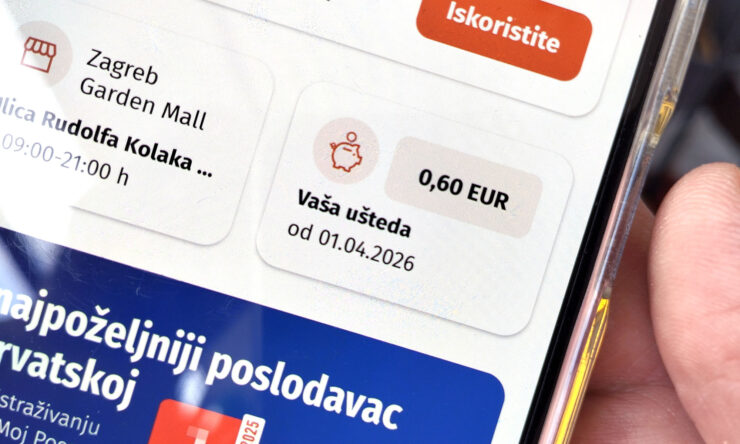 Kupac u trgovini drži mobitel s otvorenom aplikacijom Lidl programa vjernosti, prikazom uštede, kupona.
