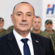 Ministar Tomo Medved ispred hrvatskih branitelja u maskirnim odorama i zamućenog logotipa HDZ-a.
