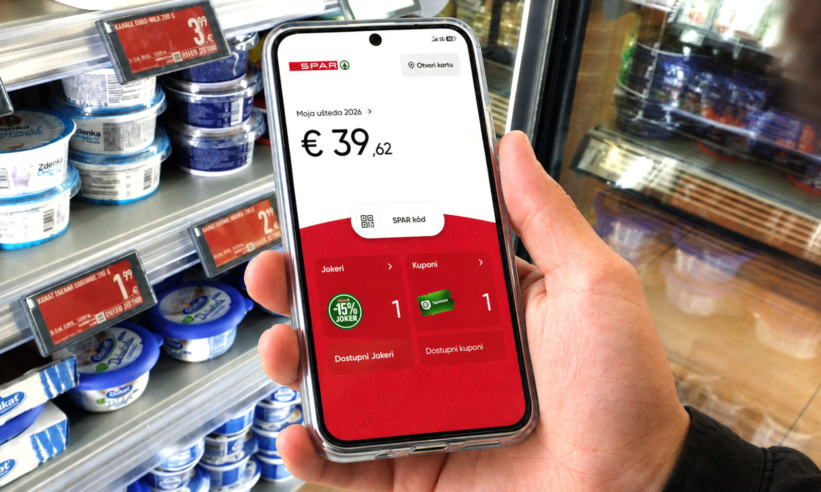 Kupac u trgovini drži mobitel s otvorenom aplikacijom SPAR programa vjernosti, prikazom uštede, kupona i Jokera.