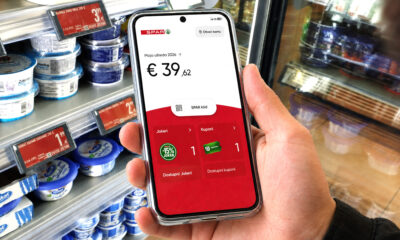 Kupac u trgovini drži mobitel s otvorenom aplikacijom SPAR programa vjernosti, prikazom uštede, kupona i Jokera.