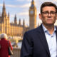 Britanski premijer Andy Burnham ispred londonskog parlamenta, sa starijim parom u pozadini.