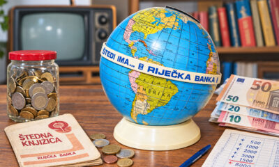 Globus kasica Riječke banke uz euro novčanice, kovanice i štednu knjižicu, kao simbol štednje i planiranja troškova u mirovini.