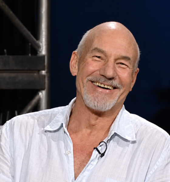 Glumac Patrick Stewart nasmiješen sjedi u televizijskom studiju.