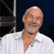 Glumac Patrick Stewart nasmiješen sjedi u televizijskom studiju.
