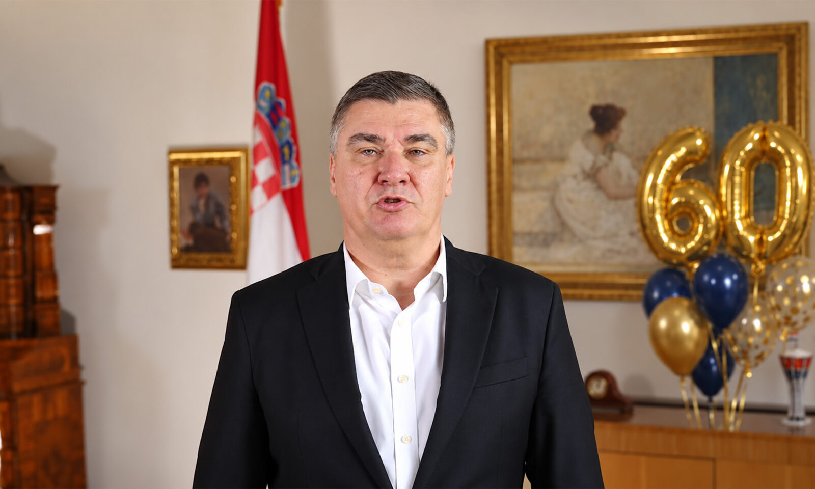 Zoran Milanović u tamnom sakou i bijeloj košulji, uz zlatne balone s brojem 60 u rođendanskoj pozadini.