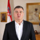 Zoran Milanović u tamnom sakou i bijeloj košulji, uz zlatne balone s brojem 60 u rođendanskoj pozadini.
